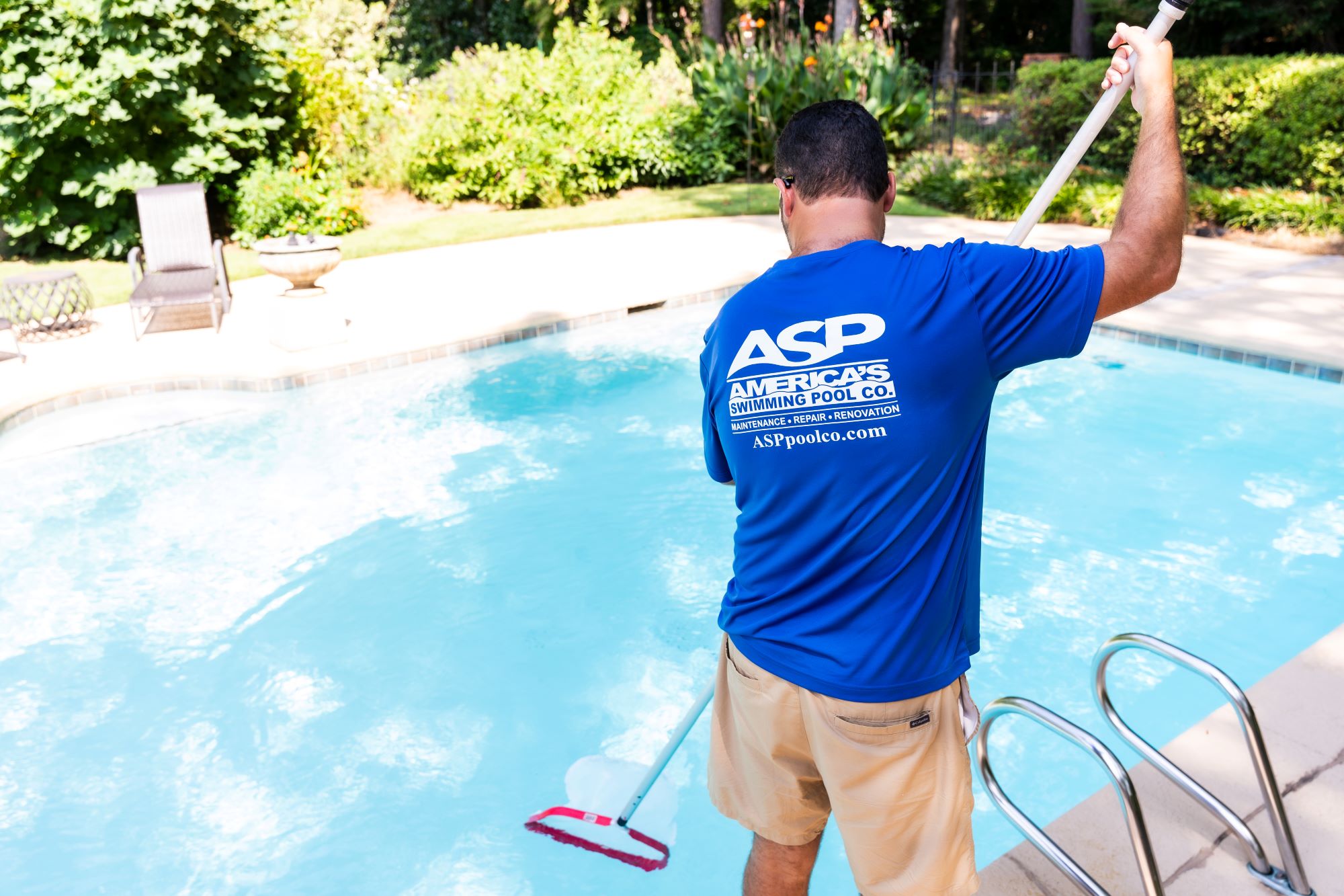 Pool service worker in an ASP uniform cleaning a pool.