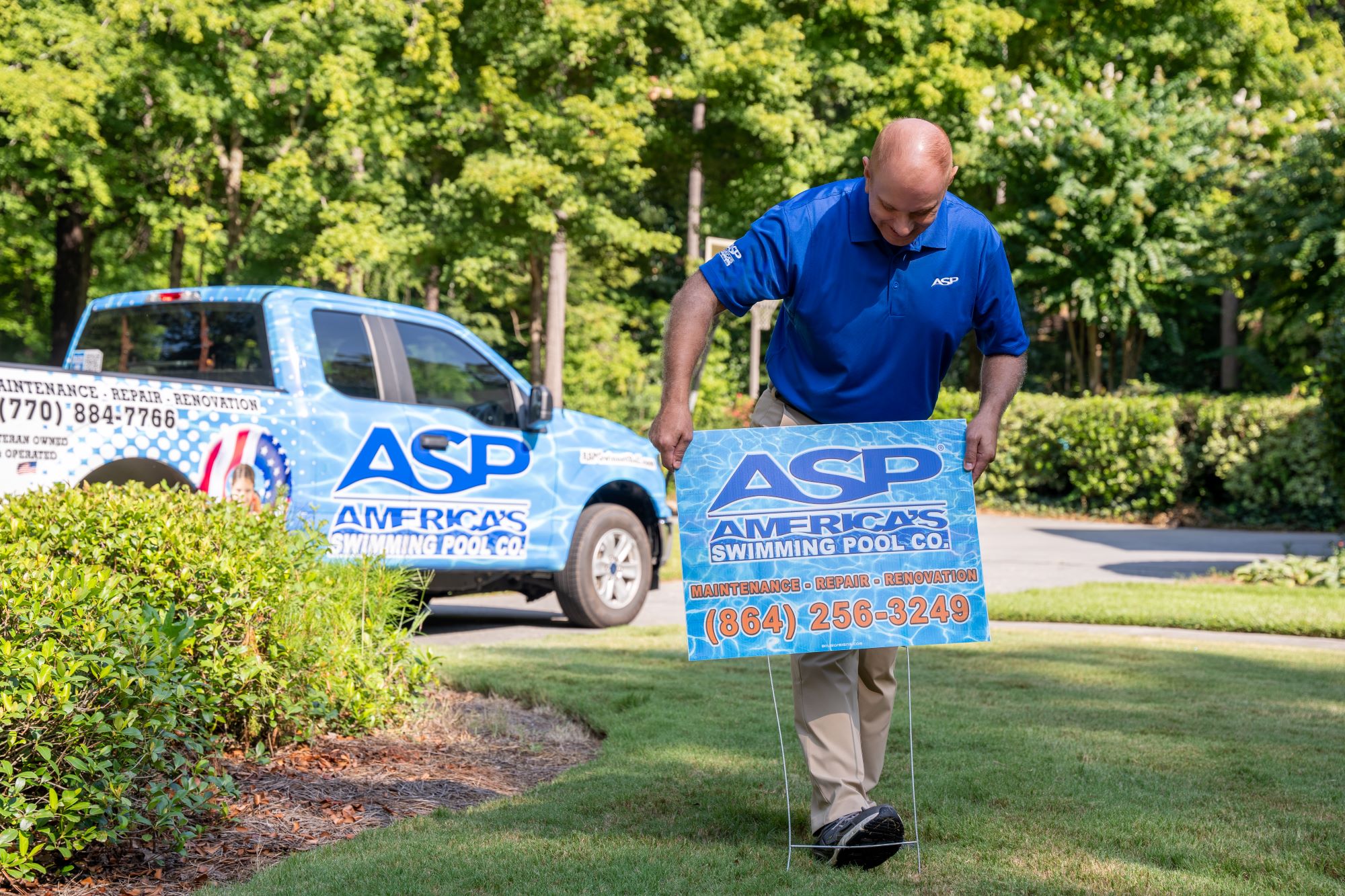 ASP franchise owner placing a branded yard sign in a lawn.